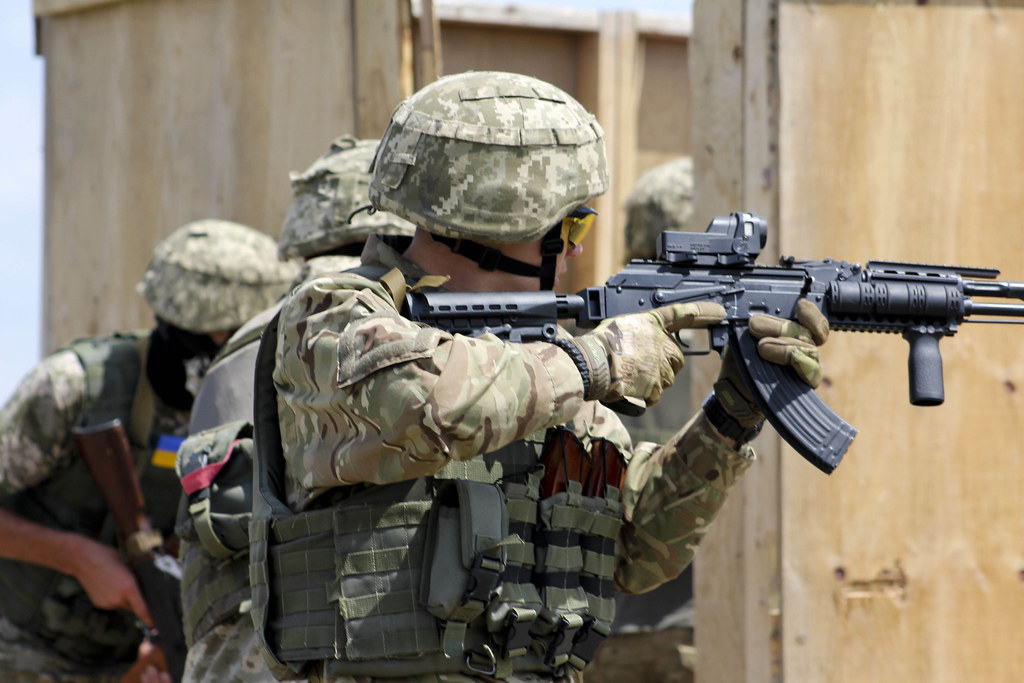 Des soldats ukrainiens nettoient et pénètrent dans une pièce.